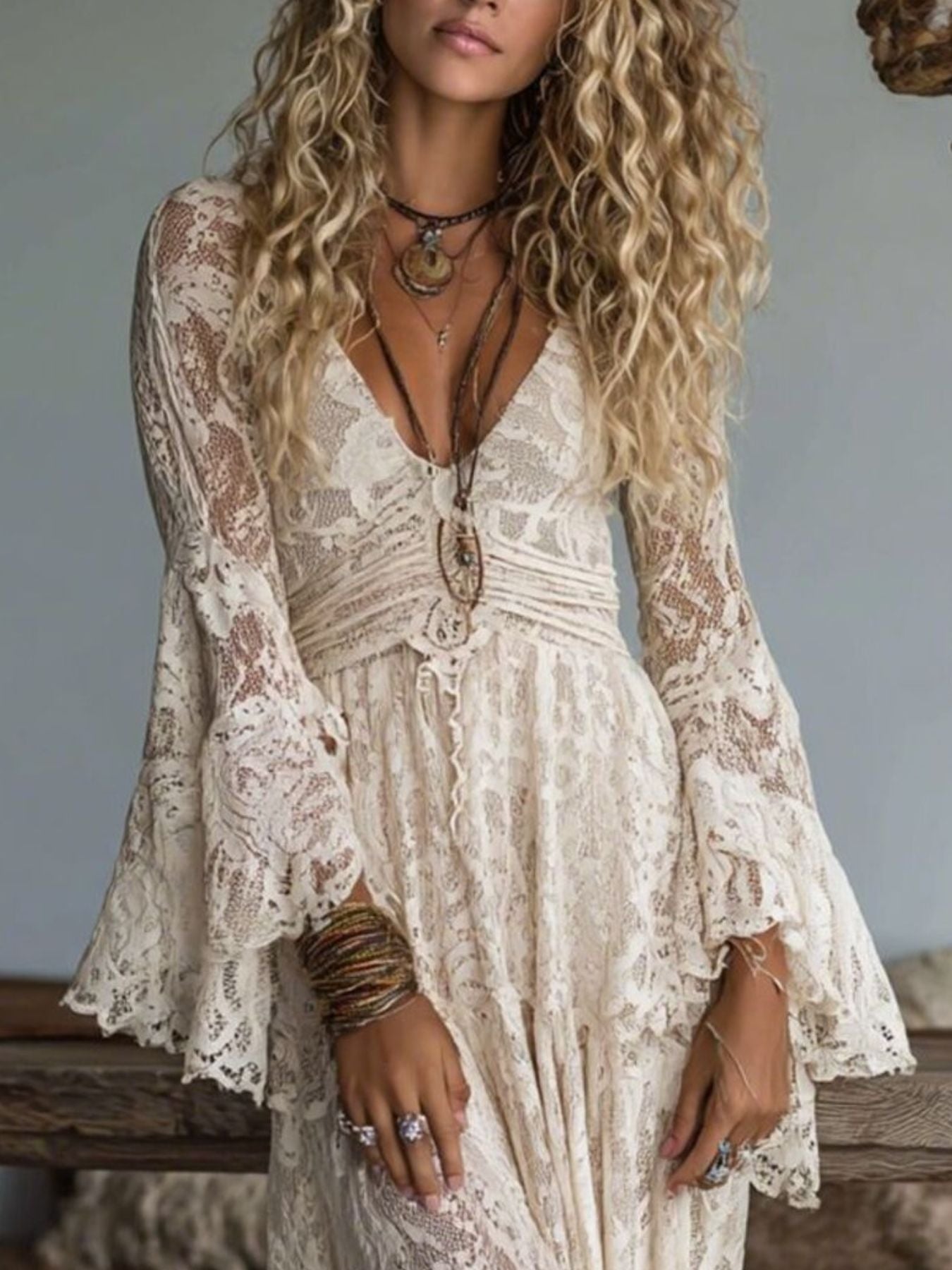 Cream lace maxi dress with deep V-neck, bell sleeves, and tiered skirt.