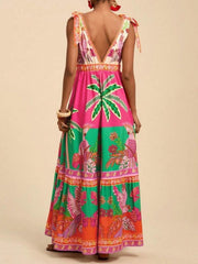 Tropical print maxi dress with tie shoulders, V-neck, and tiered skirt in pink, green, and orange.