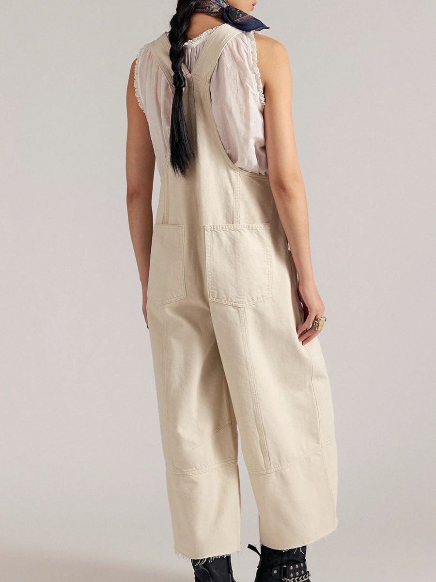 Beige denim overalls with wide legs and raw hem, featuring front pockets and adjustable straps.