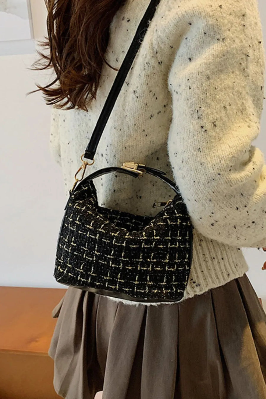 Black tweed box bag with gold clasp and detachable strap styled with a cream speckled sweater.
