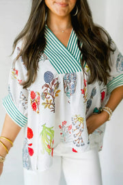 White floral print shirt with green striped contrast trim and V-neck.