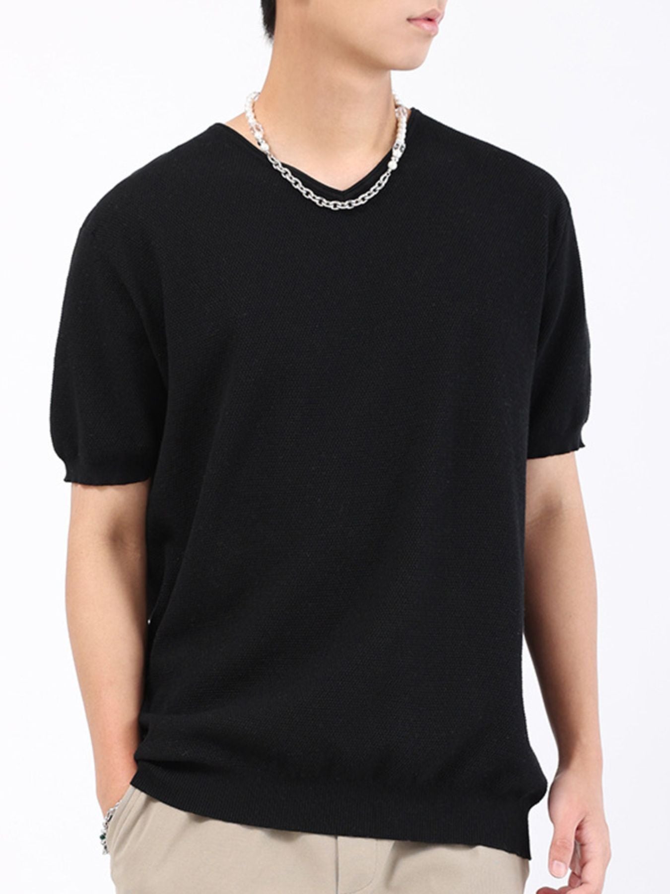 Men's black short sleeve knit t-shirt with a V-neck, styled with a silver chain necklace.