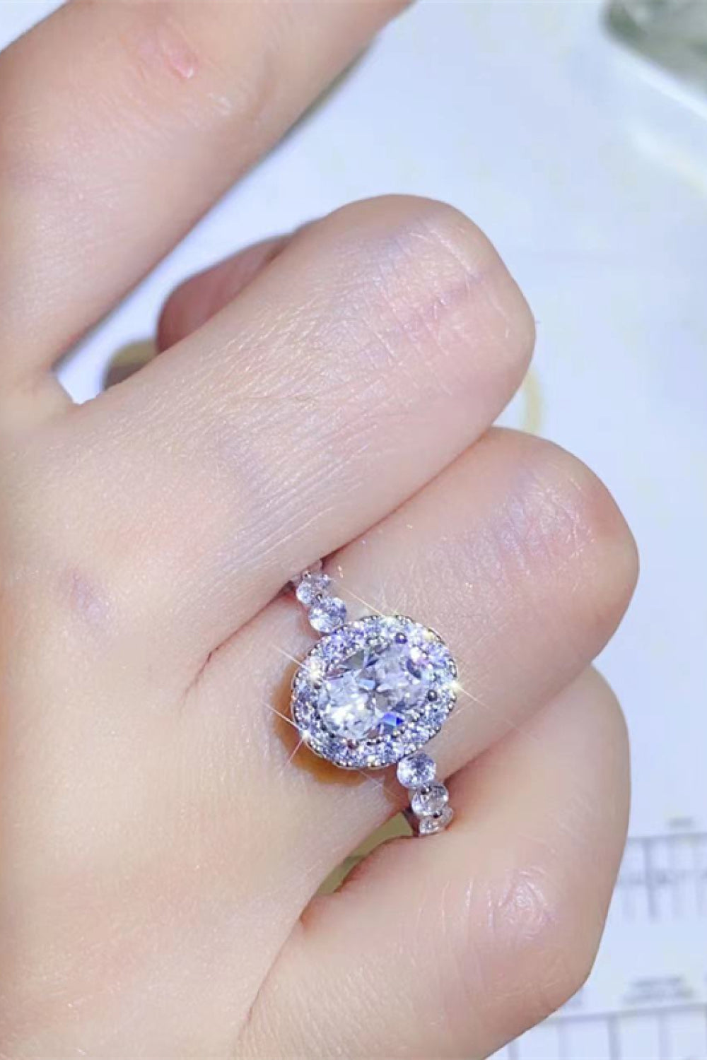 White oval moissanite halo ring with sparkling accent stones on band