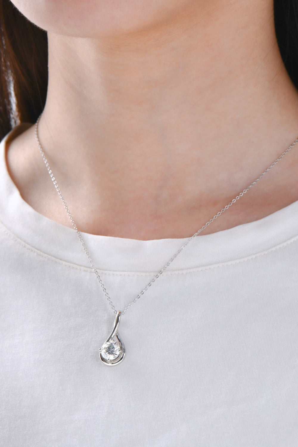 Silver teardrop pendant necklace with a clear gemstone on a delicate chain.