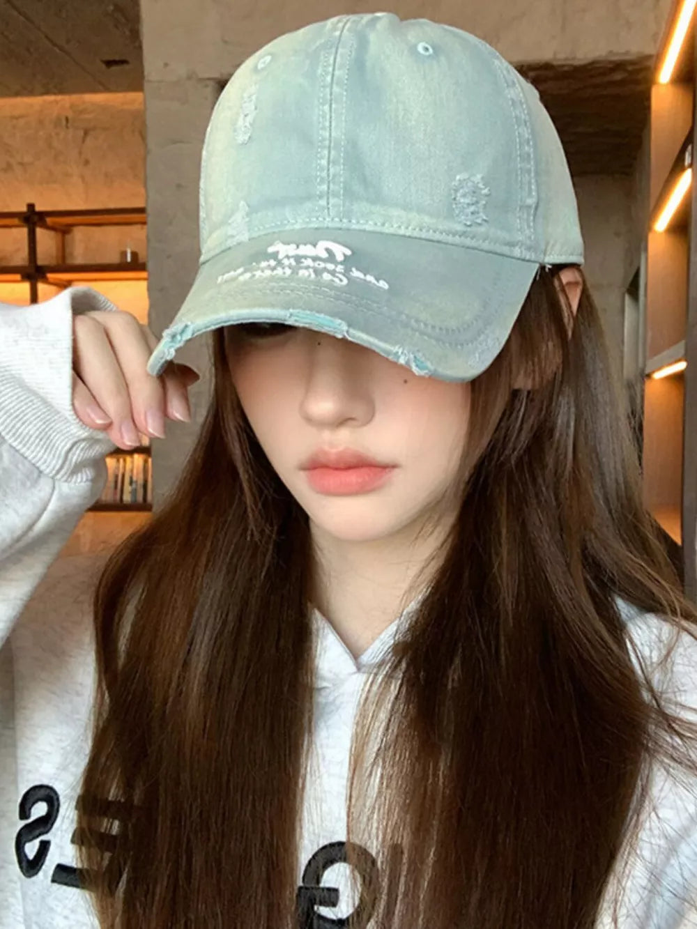 Distressed baseball hat in dirty blue cotton with embroidered detail and frayed brim.