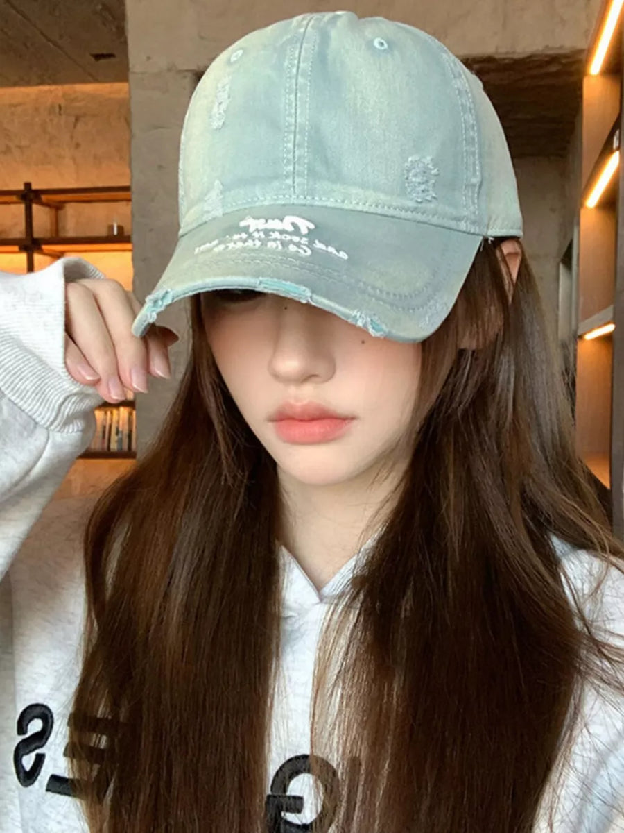 Distressed baseball hat in dirty blue cotton with embroidered detail and frayed brim.