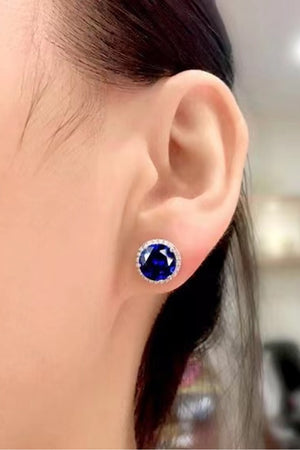 Blue sapphire halo stud earrings with diamond accents.