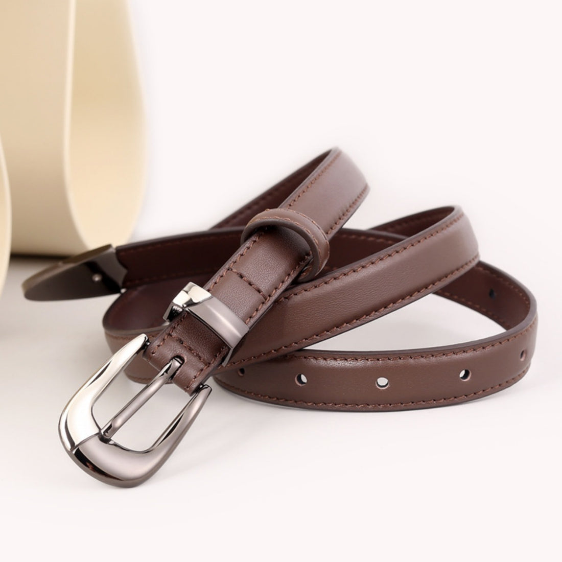 Brown cowhide leather belt with a sleek metal buckle and stitching detail.