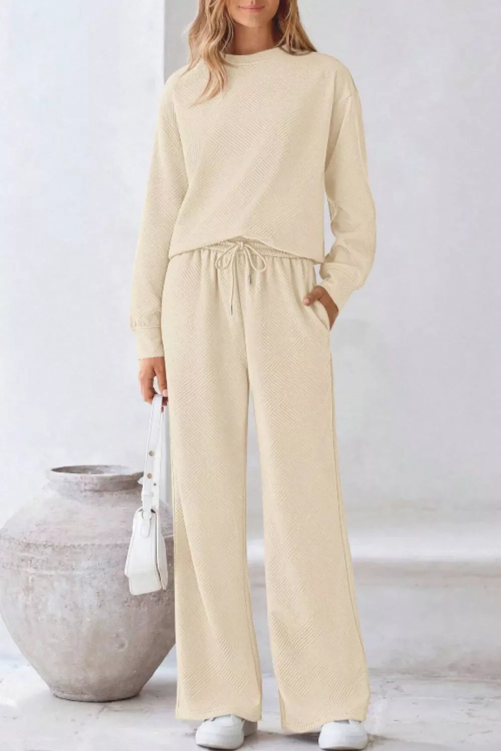 Apricot loungewear set with textured fabric, crew neck sweatshirt, and drawstring wide-leg pants.