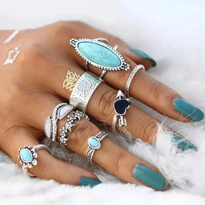 Bohemian silver rings with turquoise stones and assorted designs on a hand.