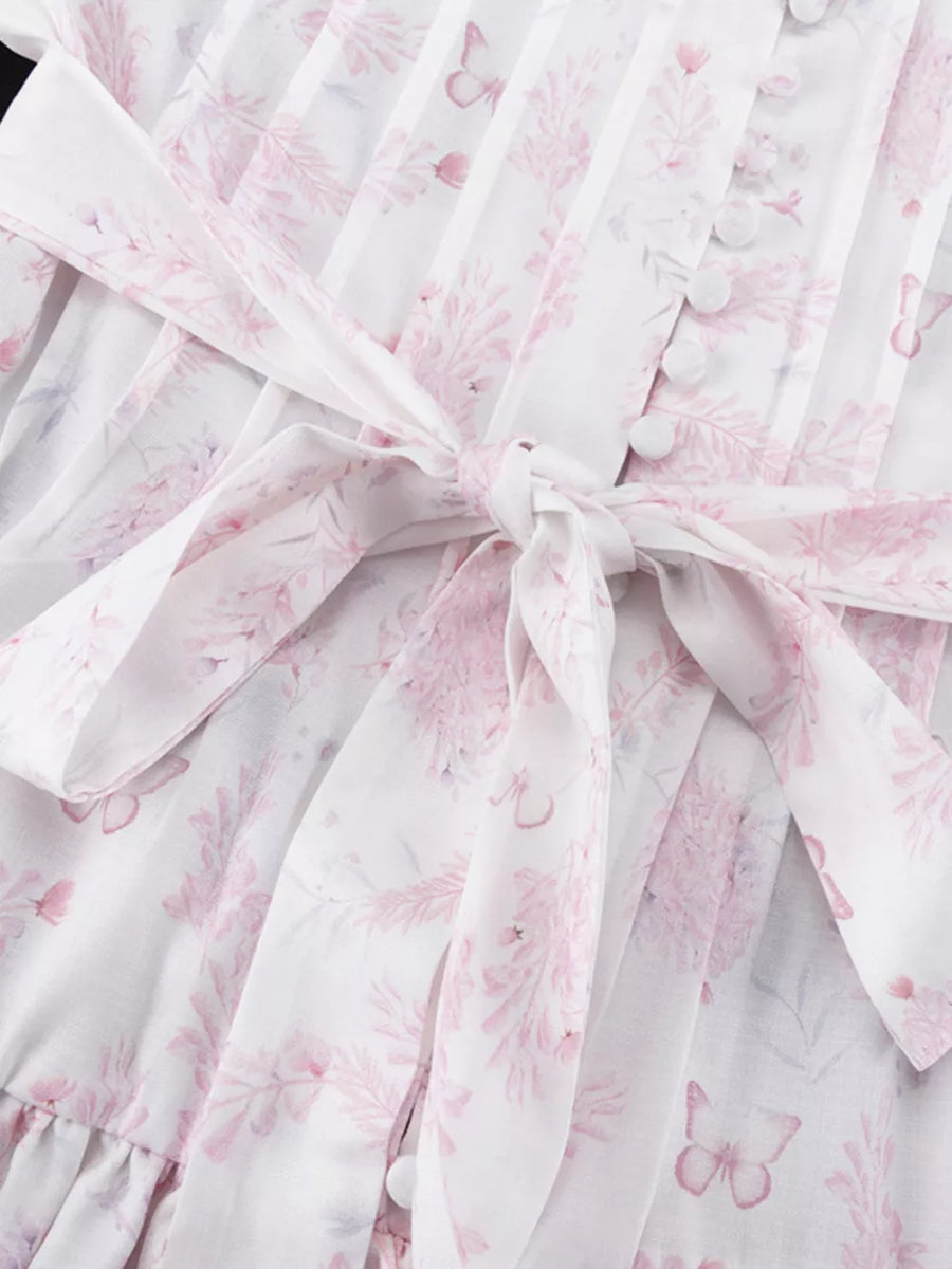 White dress with pink floral print, tie waist, and button front.