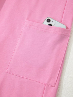 Pink cotton romper with a functional pocket holding a smartphone.