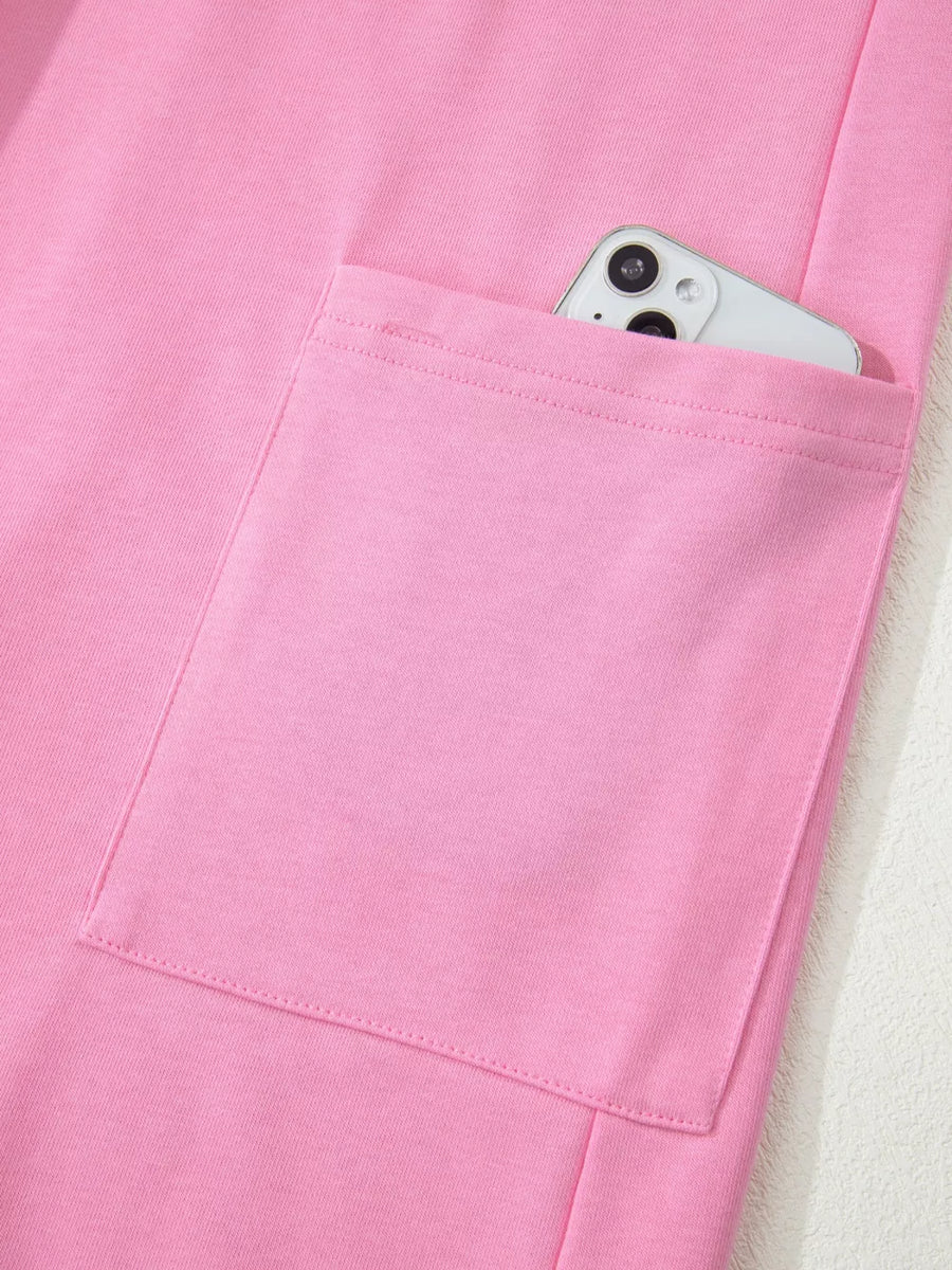 Pink cotton romper with a functional pocket holding a smartphone.