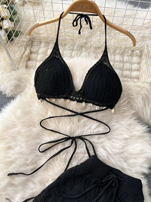 Black crochet halter bikini top with shell trim and tie waist, wide-leg pants.