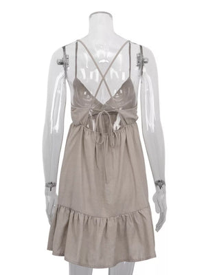 Tan linen blend mini dress with crisscross straps, tie back, and ruffled hem