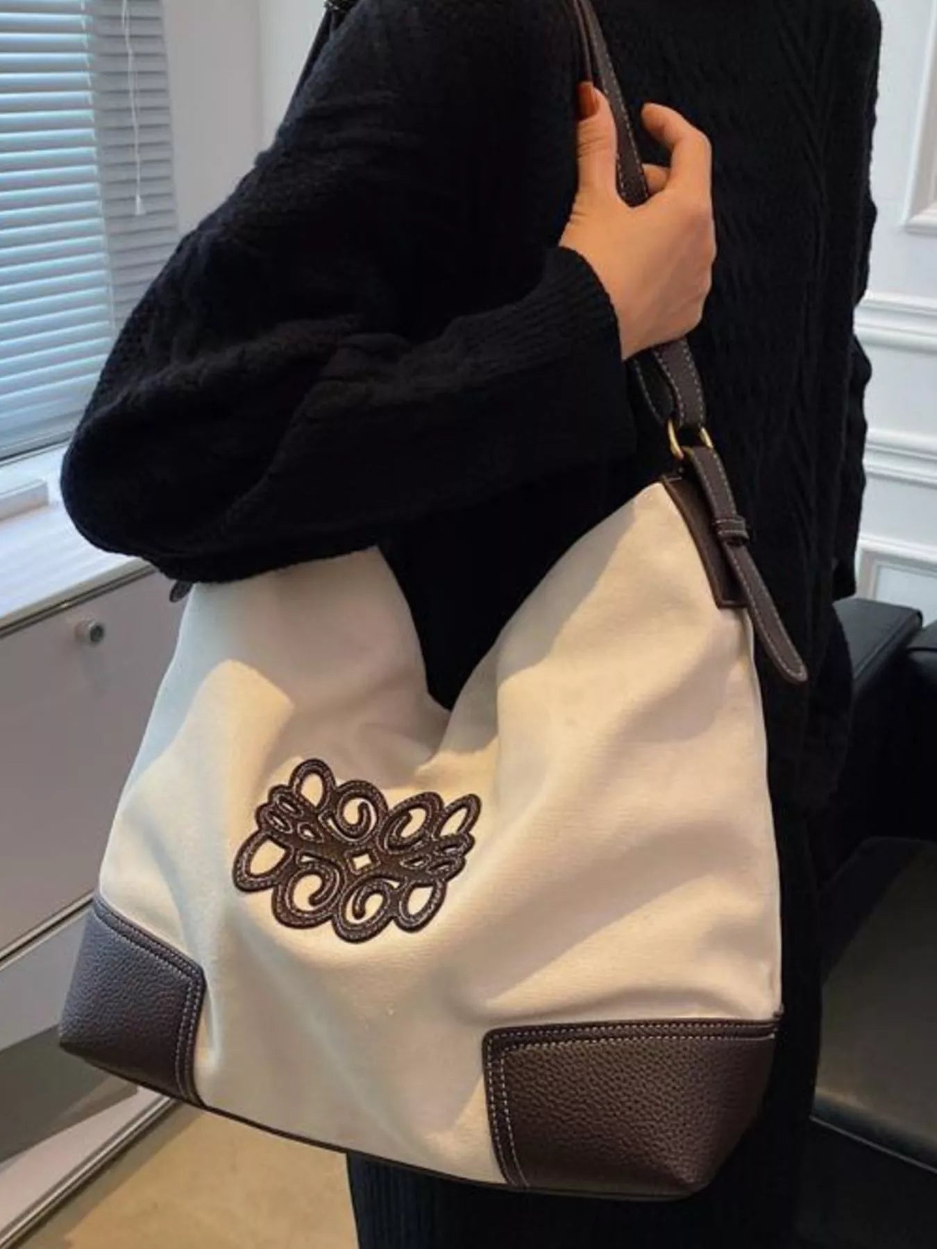 White canvas tote bag with brown leather trim and embroidered logo detail