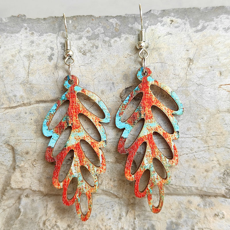 Patina leaf laser-cut drop earrings with red and blue distressed pattern.