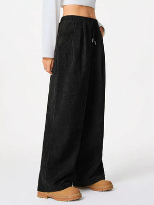 Black corduroy pants with drawstring waist and wide leg, styled with a white top.