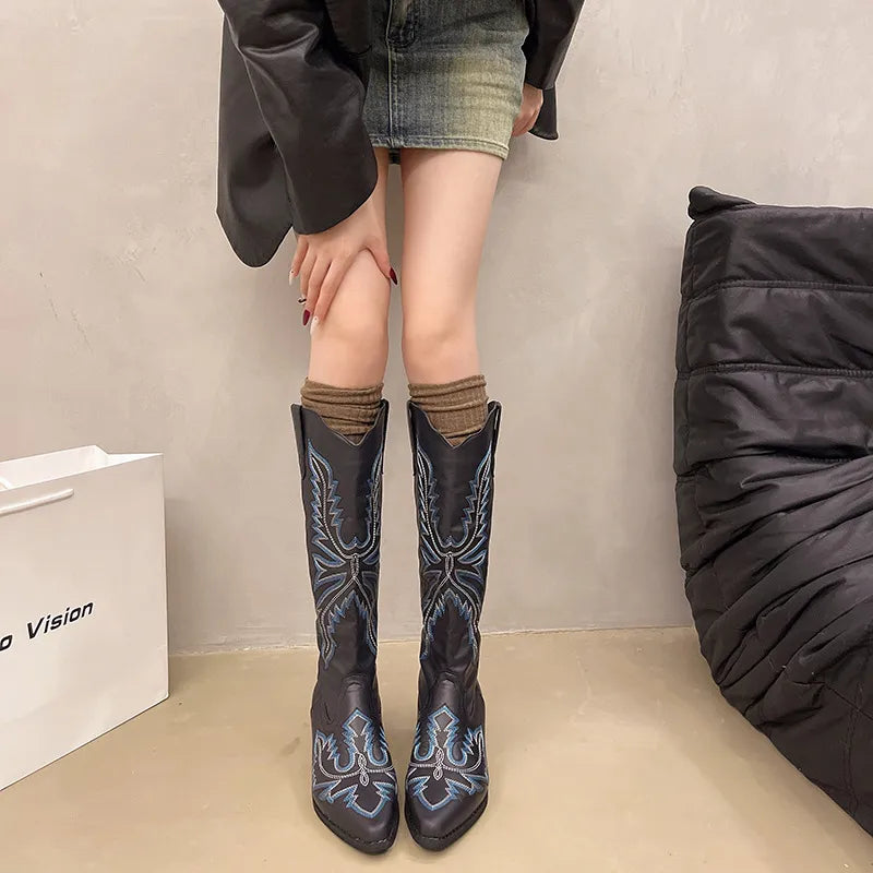Black embroidered western pointed-toe knee boots with blue stitching detail.