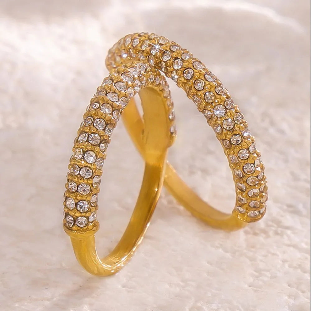 Gold pavé zirconia band ring with clear stones on a textured surface.