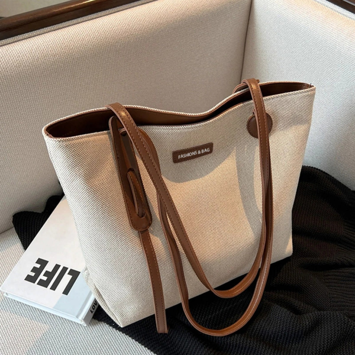 Large canvas shoulder bag with leather trim and brown straps.