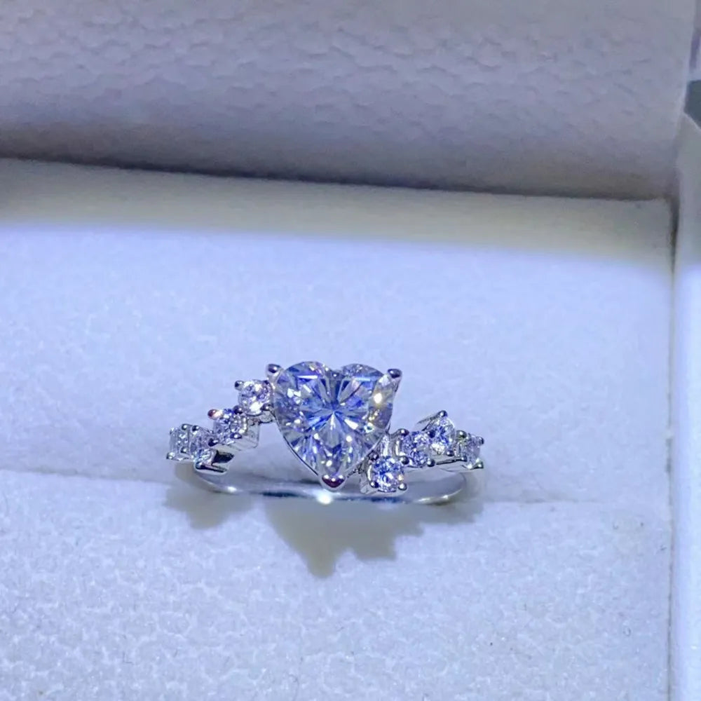 Silver ring with a heart-cut diamond cluster and small accent diamonds.