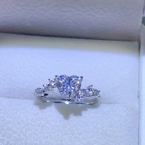 Silver ring with a heart-cut diamond cluster and small accent diamonds.