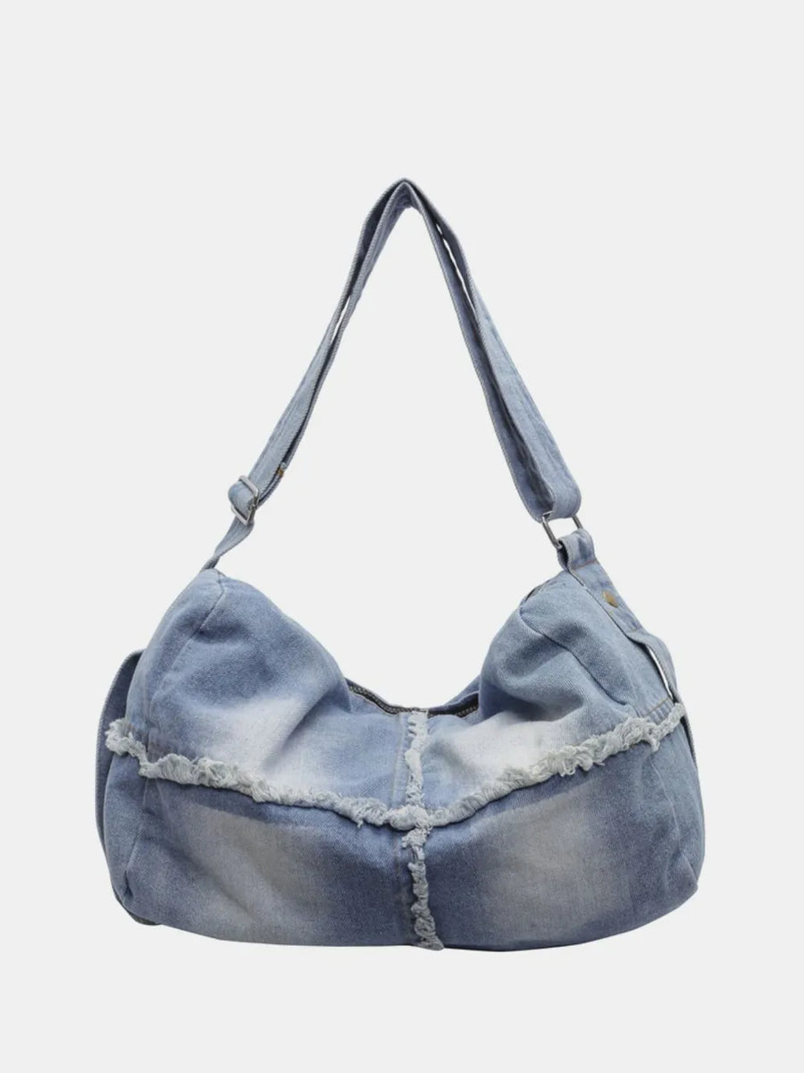 Light wash denim crossbody bag with frayed edges and slouchy silhouette.