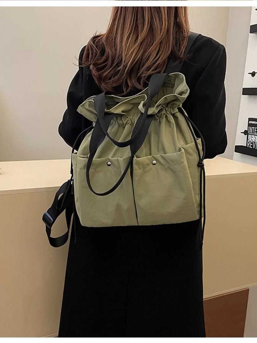 Green drawstring backpack with two front pockets and black straps.