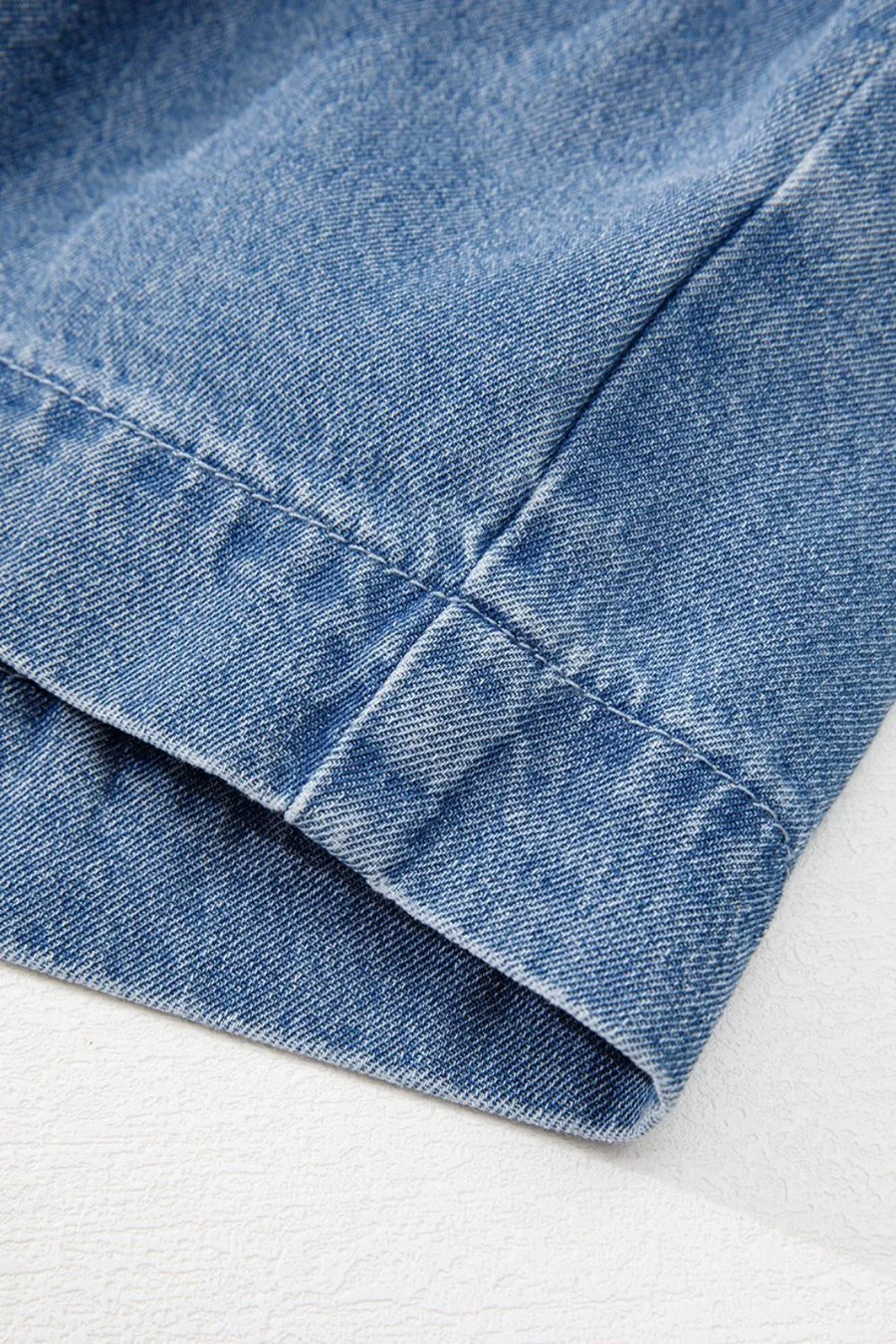 Denim peplum blouse in medium blue with visible stitching detail.