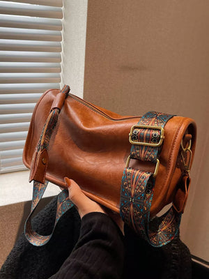 Brown crossbody bag with textured strap and adjustable strap.