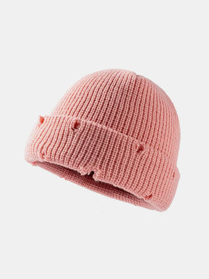 Pink ribbed knit beanie with distressed details and a cuffed brim.