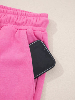 Hot pink casual pants with elastic waistband and side pocket holding a smartphone.