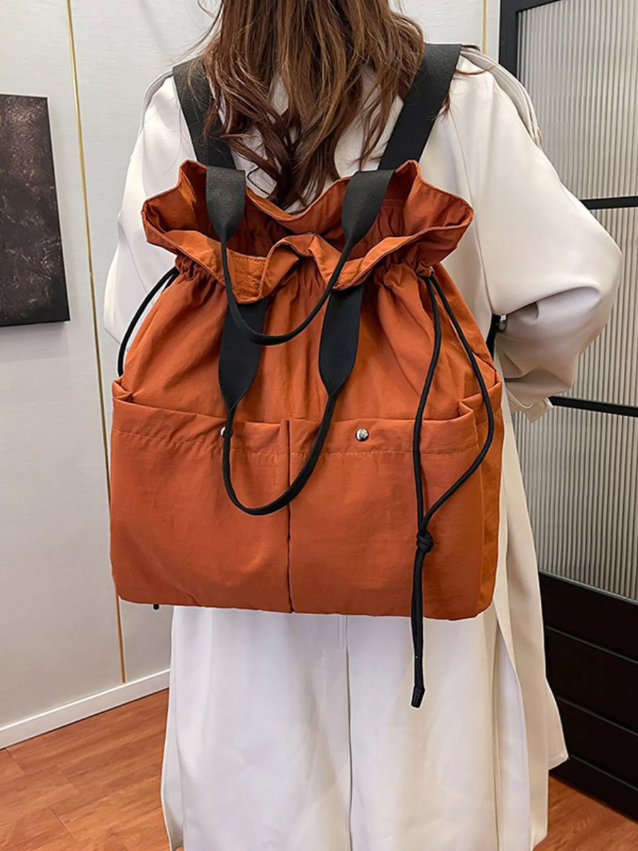 Orange drawstring backpack with front pockets and black straps