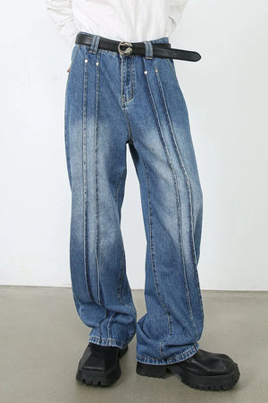 Medium wash denim trousers with vertical seams and a relaxed fit.