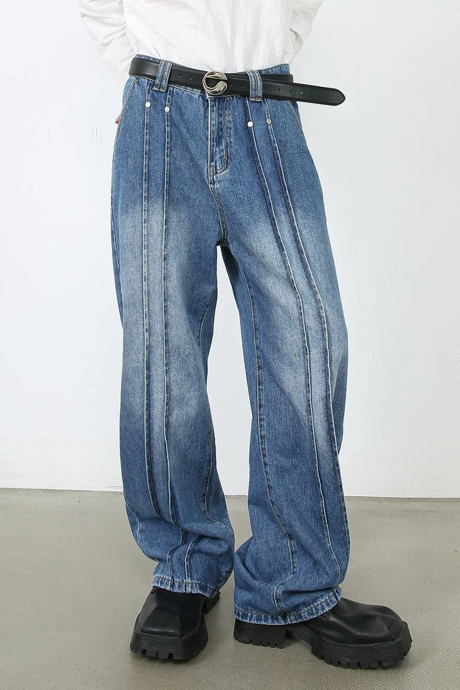 Medium wash denim trousers with vertical seams and a relaxed fit.