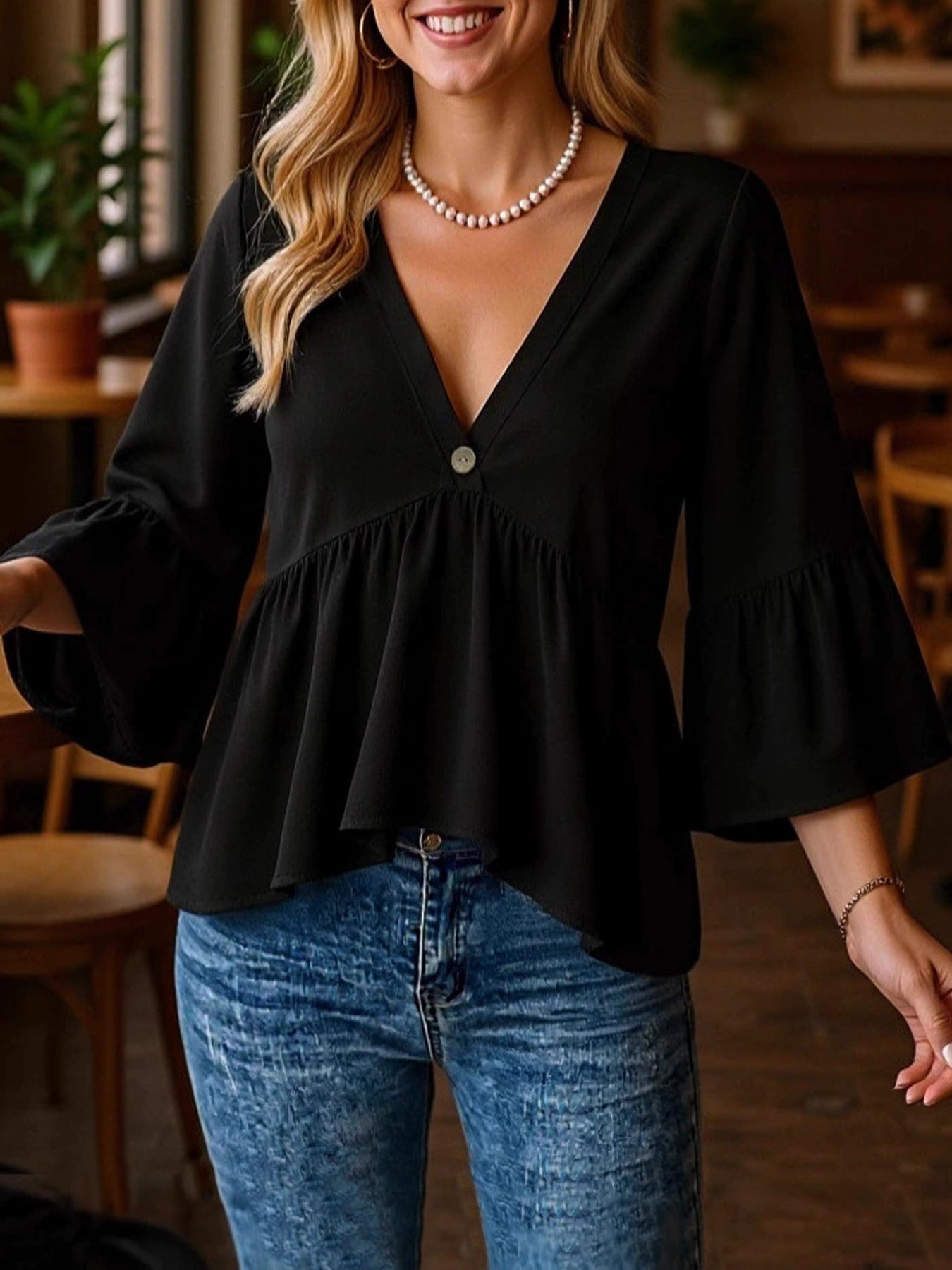 Black V-neck blouse with flounce sleeves and a single button detail.