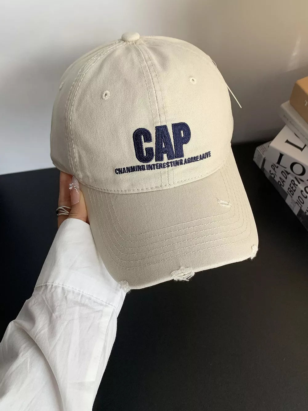 Embroidered cotton baseball hat in cream white with distressed brim and navy blue text.