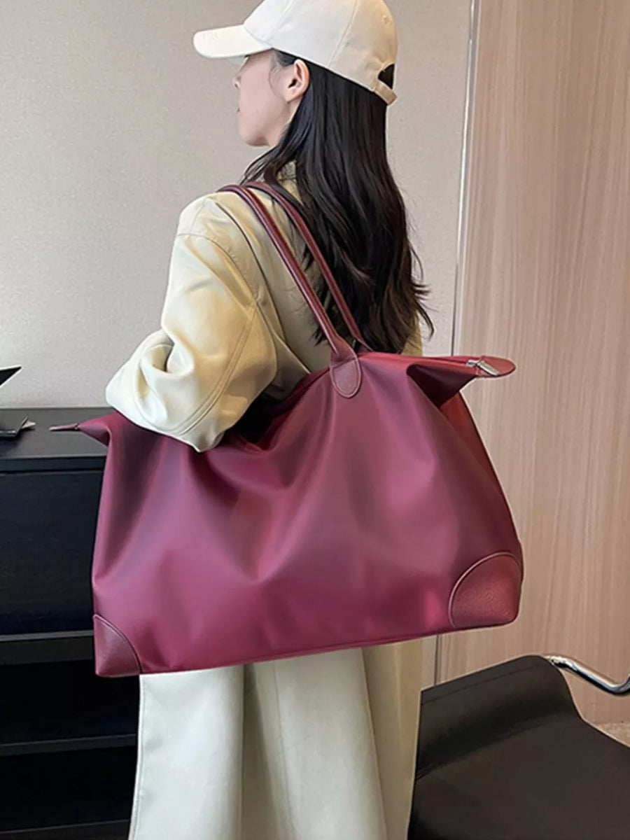 Burgundy Oxford cloth travel tote with leather trim and shoulder straps.