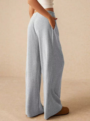 Gray ribbed wide-leg drawstring pants with pockets, styled casually.