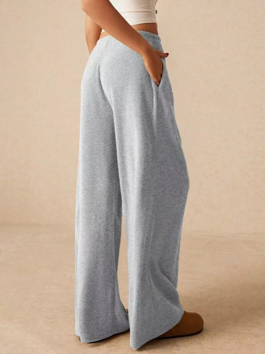Gray ribbed wide-leg drawstring pants with pockets, styled casually.
