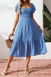 Blue floral smocked square neck dress with short flutter sleeves and tiered skirt.