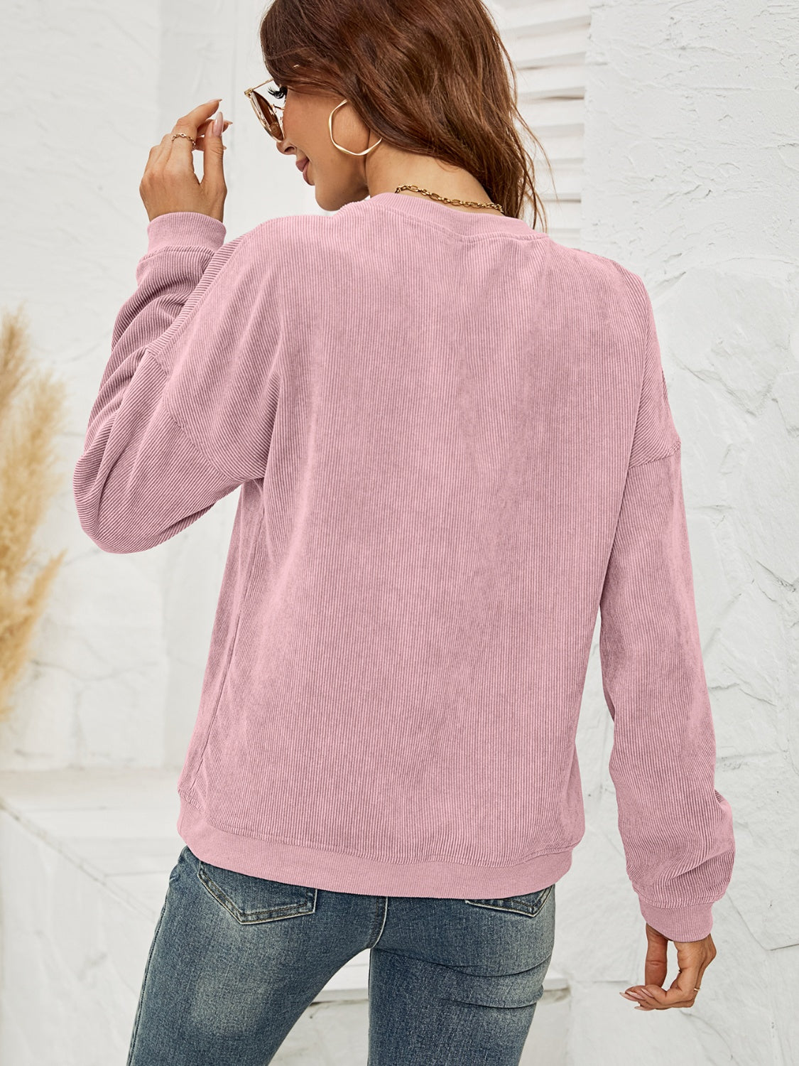 Dusty Pink corduroy sweatshirt with crewneck and long sleeves, styled with jeans.