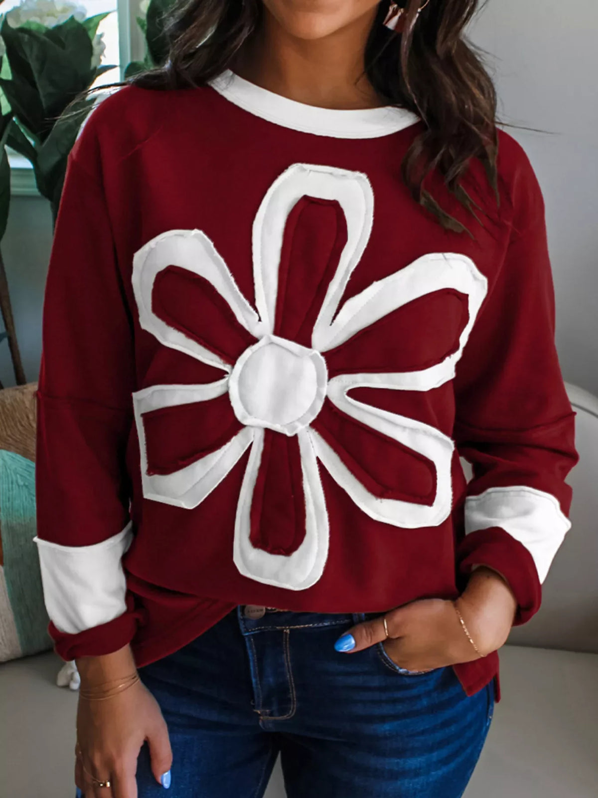 Burgundy long-sleeve top with a large white flower applique and white cuffs.