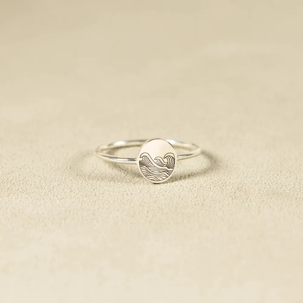 Silver ring with engraved wave pattern on oval face