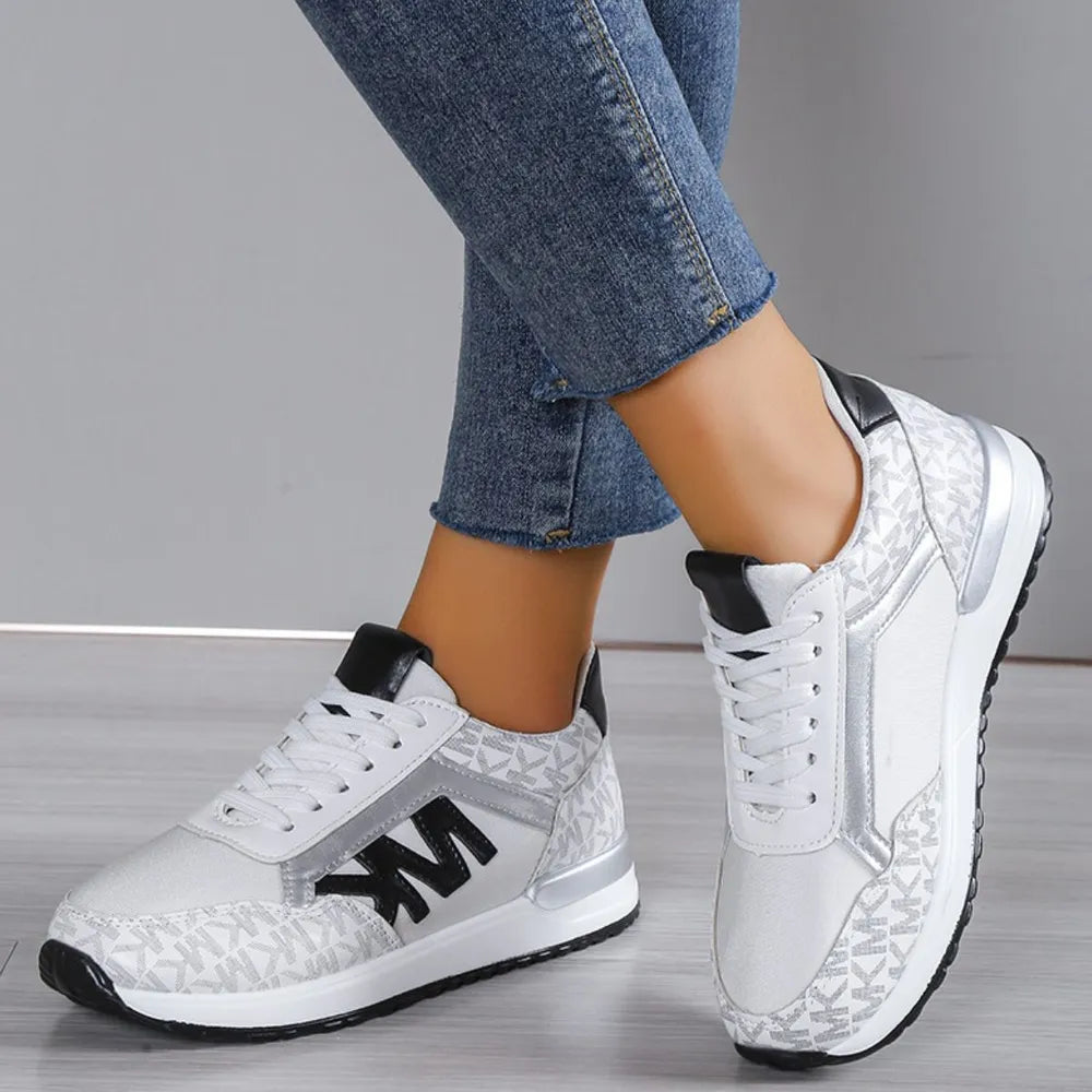 White and silver monogram runner sneakers with black accents and logo detail.