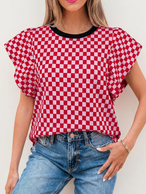 Red and white checkered print shirt with ruffle sleeves and black neckline.