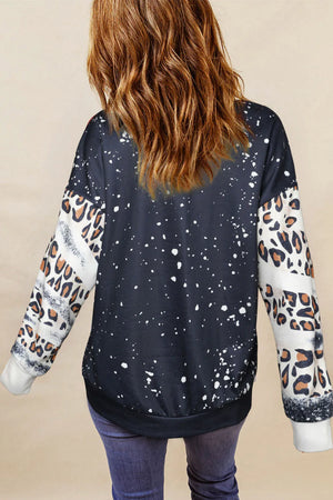 Black graphic sweatshirt with splatter print and leopard print sleeves.