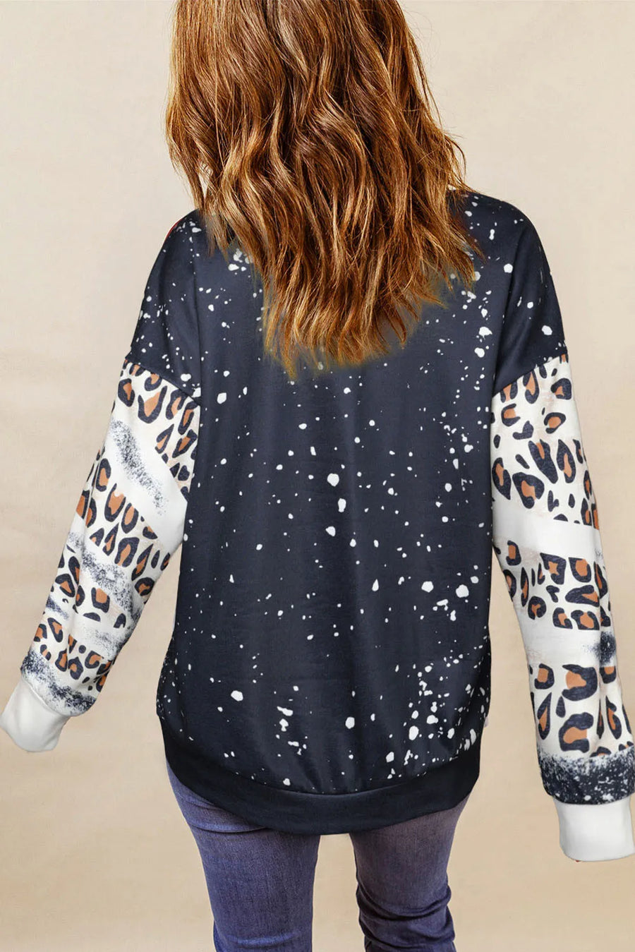 Black graphic sweatshirt with splatter print and leopard print sleeves.