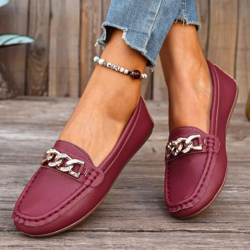 Burgundy round-toe loafers with gold chain detail and textured finish.